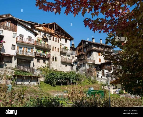 Casas tradicionales de Tonadico con muros claros, balcones y galerías de madera, huertas y follaje otoñal. Foto: Reda and Co, Alamy 2E250E5, 14 de octubre de 2018; se conserva la marca de agua.