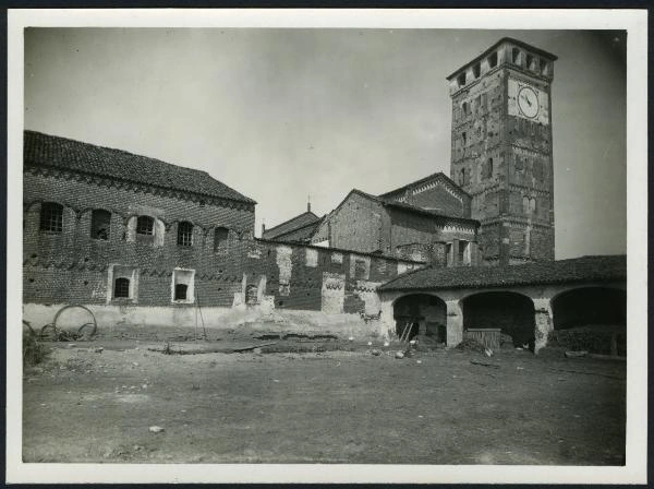 Vista histórica del lado posterior de la abadía de San Nazzaro Sesia: patio, edificios de ladrillo y torre campanario con reloj. Fotógrafo no identificado, primera mitad del siglo XX. Civico Archivio Fotografico de Milán, Raccolta Iconografica, RI 13199/1; Lombardia Beni Culturali, IMM-3a010-0013293.
