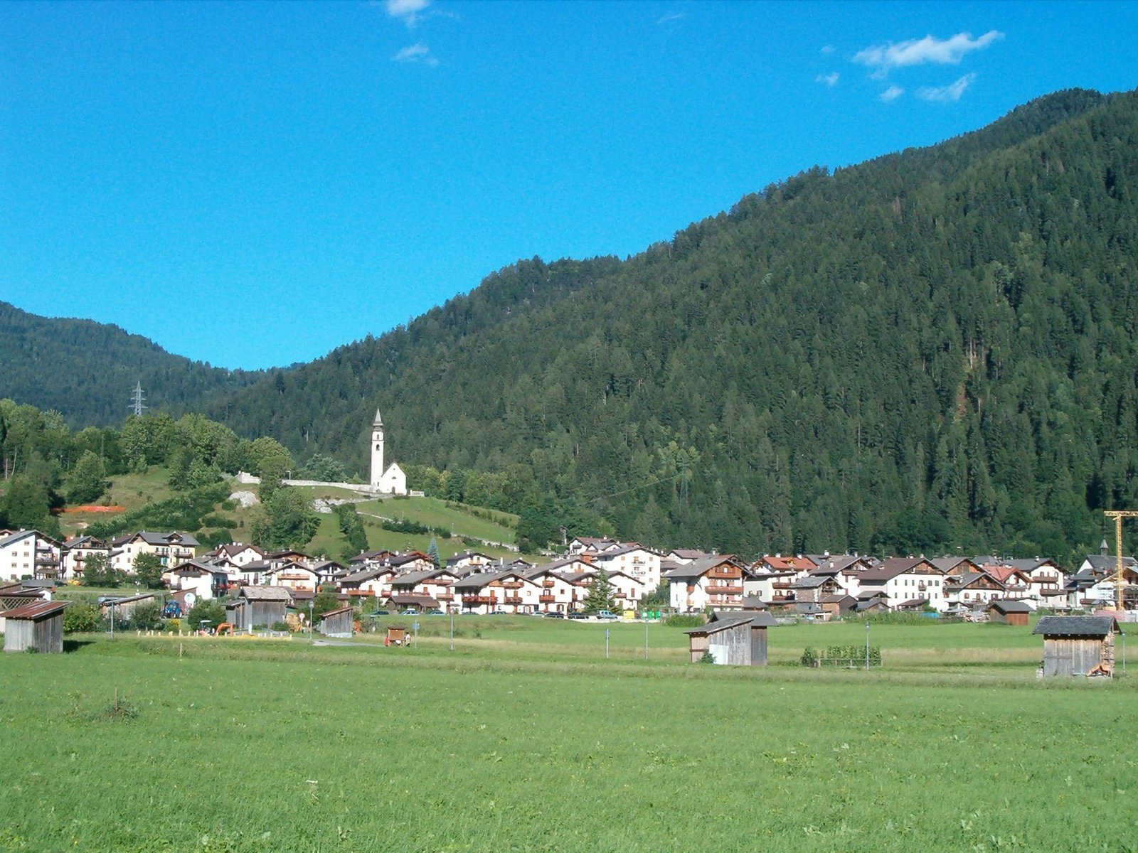 Vista de Tonadico con sus casas y montañas del valle de Primiero. Foto: Alesvp, 2006; Wikimedia Commons.