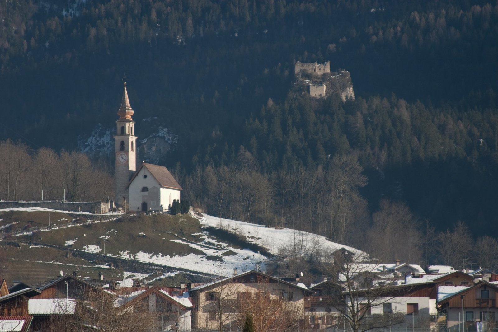 Iglesia de San Vittore y Corona en la colina de Tonadico, con nieve y paisaje alpino. Foto: Alessandro (Obliot), 2008; Wikimedia Commons.